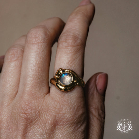 Handmade serpent ring set with moonstone, sculptural wax carved design in brass, worn on hand.
