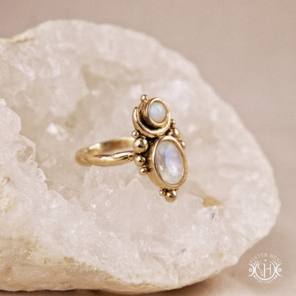 Hand-carved Nyx ring with opal and moonstone in brass, sculptural crescent design, on crystal.
nyx-ring-large-scale-moonstone-opal-close