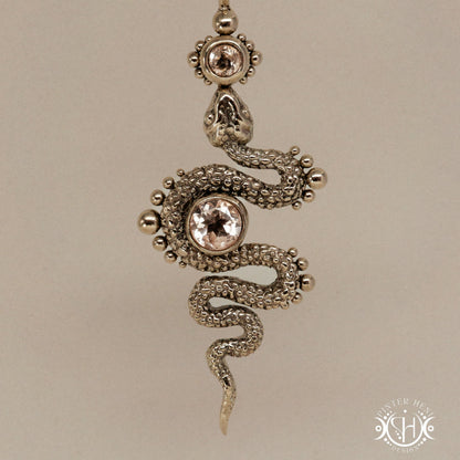 Textured snake-shaped pendant with morganite on a beige background