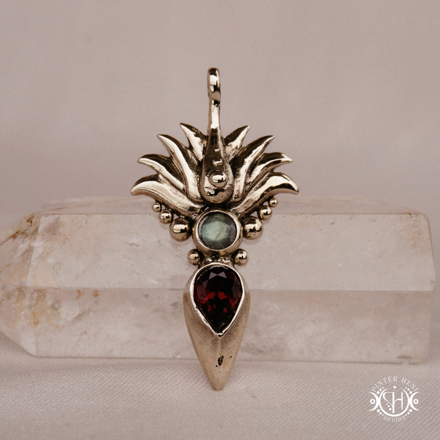 Handmade Agave pendant with garnet stone, sculptural desert-inspired botanical necklace, on crystal.
