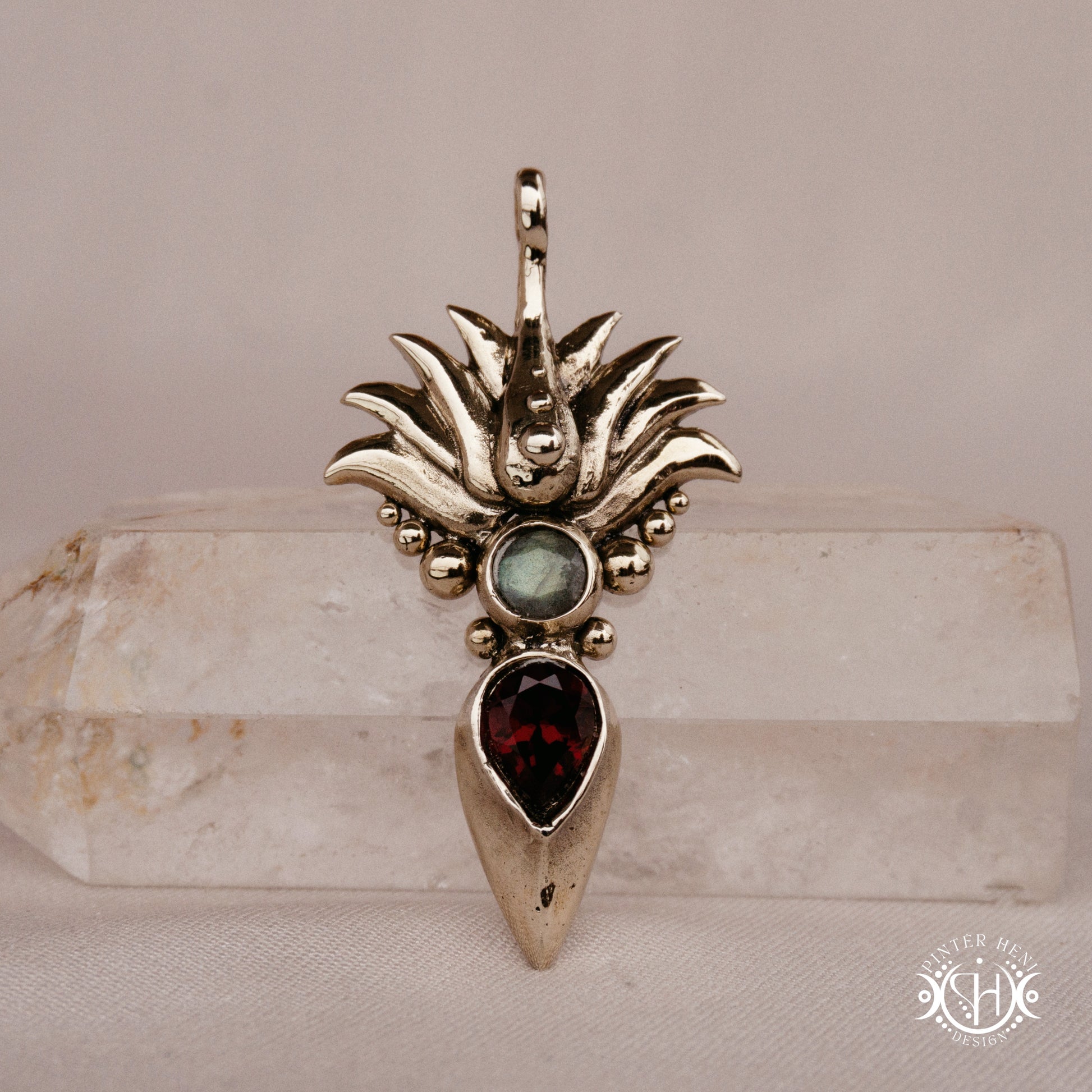 Handmade Agave pendant with garnet stone, sculptural desert-inspired botanical necklace, on crystal.