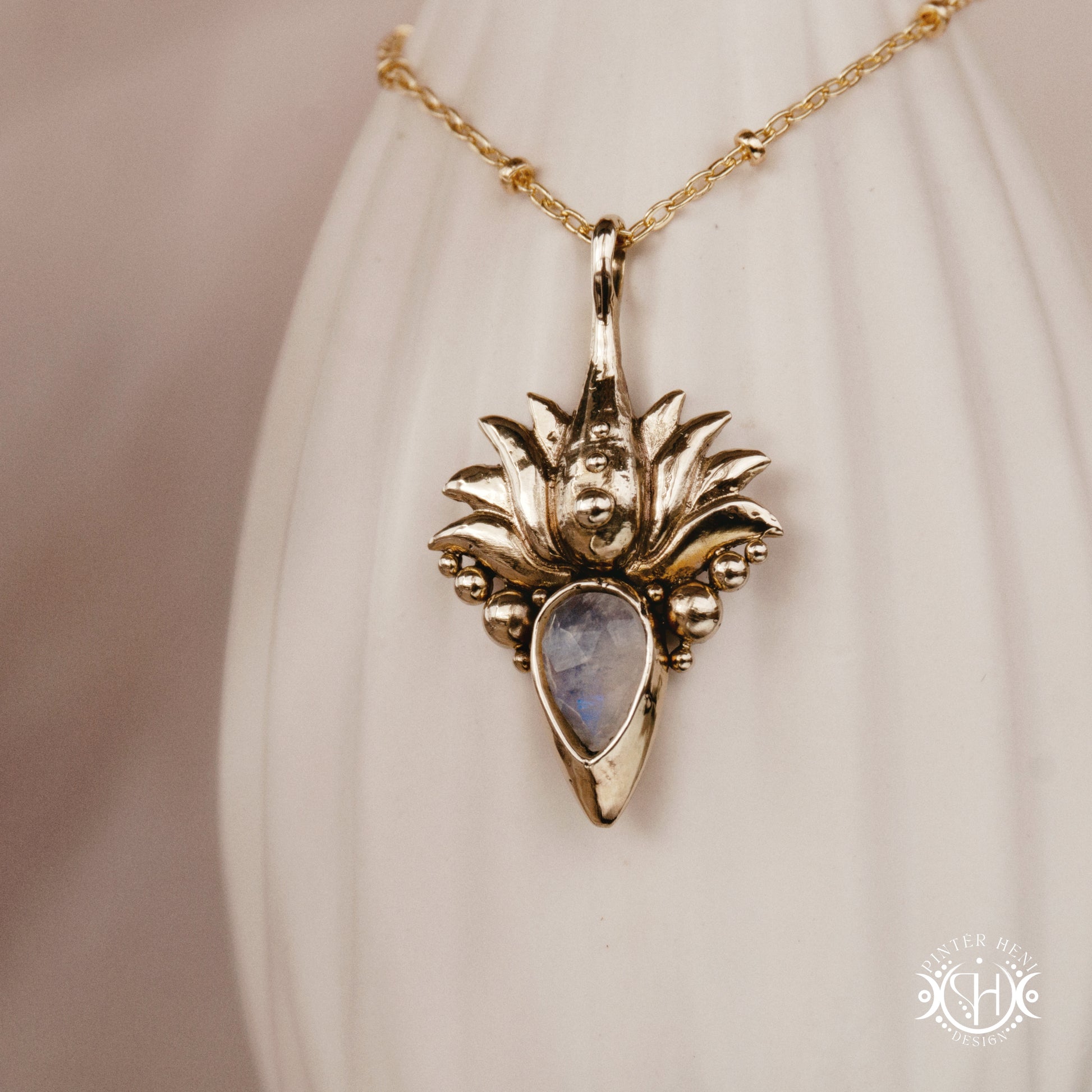 Hand-carved Agave pendant inspired by desert plant structure, sculptural botanical necklace in brass, on a ceramic vase