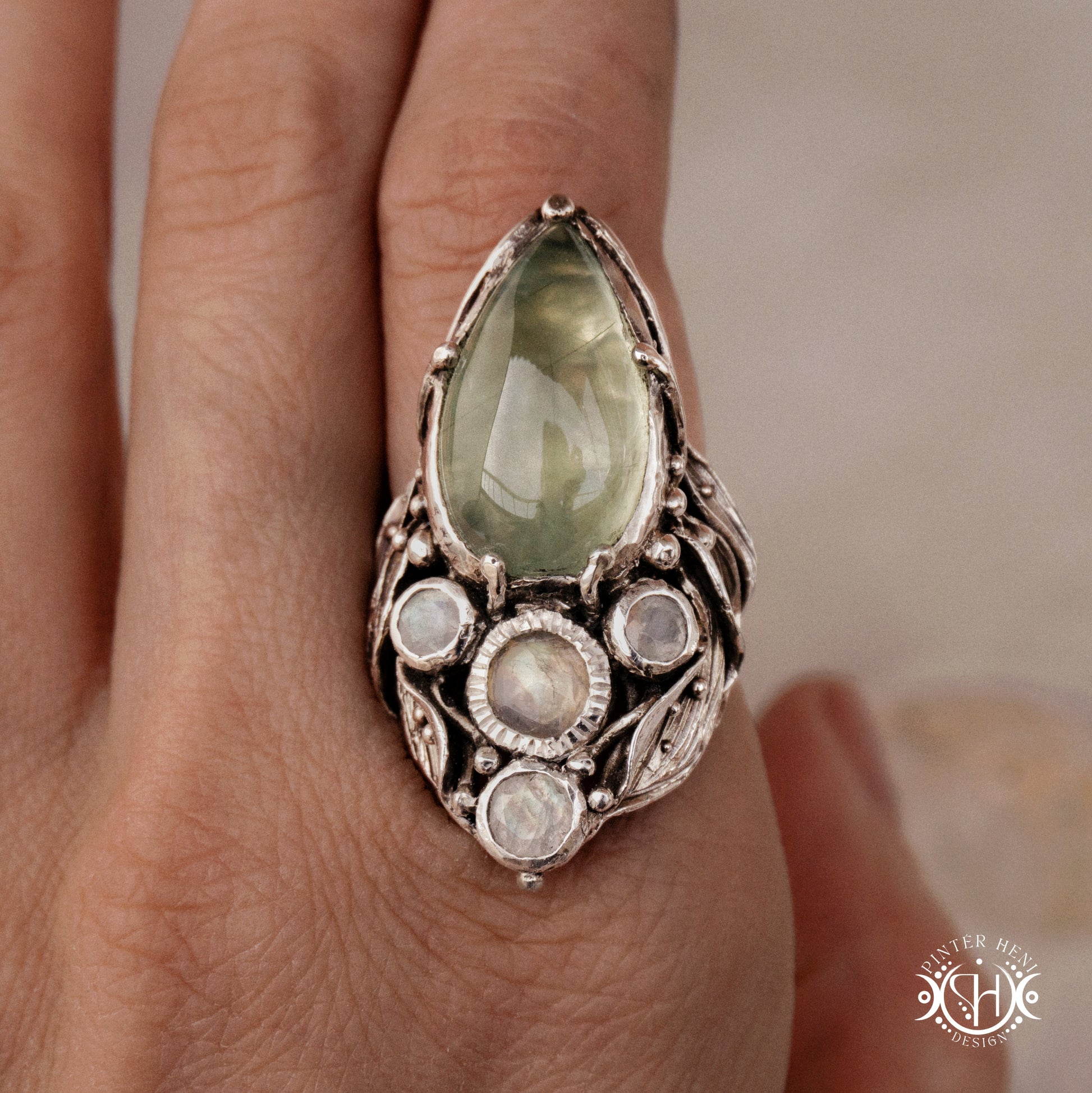 One-of-a-kind sterling silver ring with pear-shaped prehnite and moonstones in vertical sculptural setting.