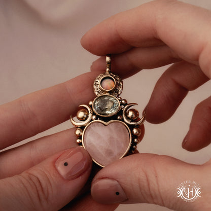 Hand-carved Aphrodite pendant with rose quartz, opal and prasiolite, held in hand.