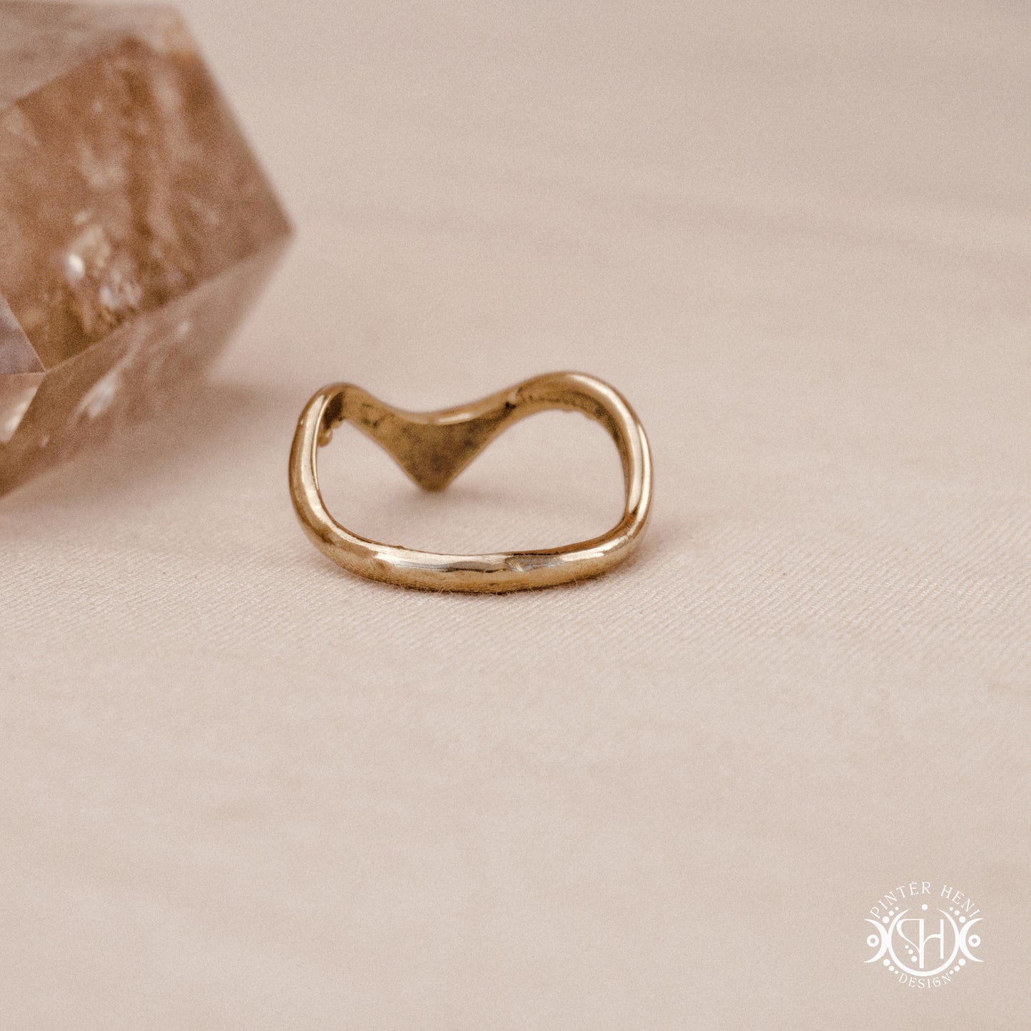 Arc Ring organic sculptural wave ring handmade in brass with rounded nodular details, on beige surface.