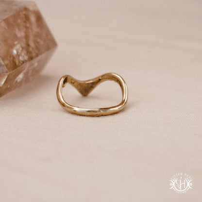 Arc Ring organic sculptural wave ring handmade in brass with rounded nodular details, on beige surface.