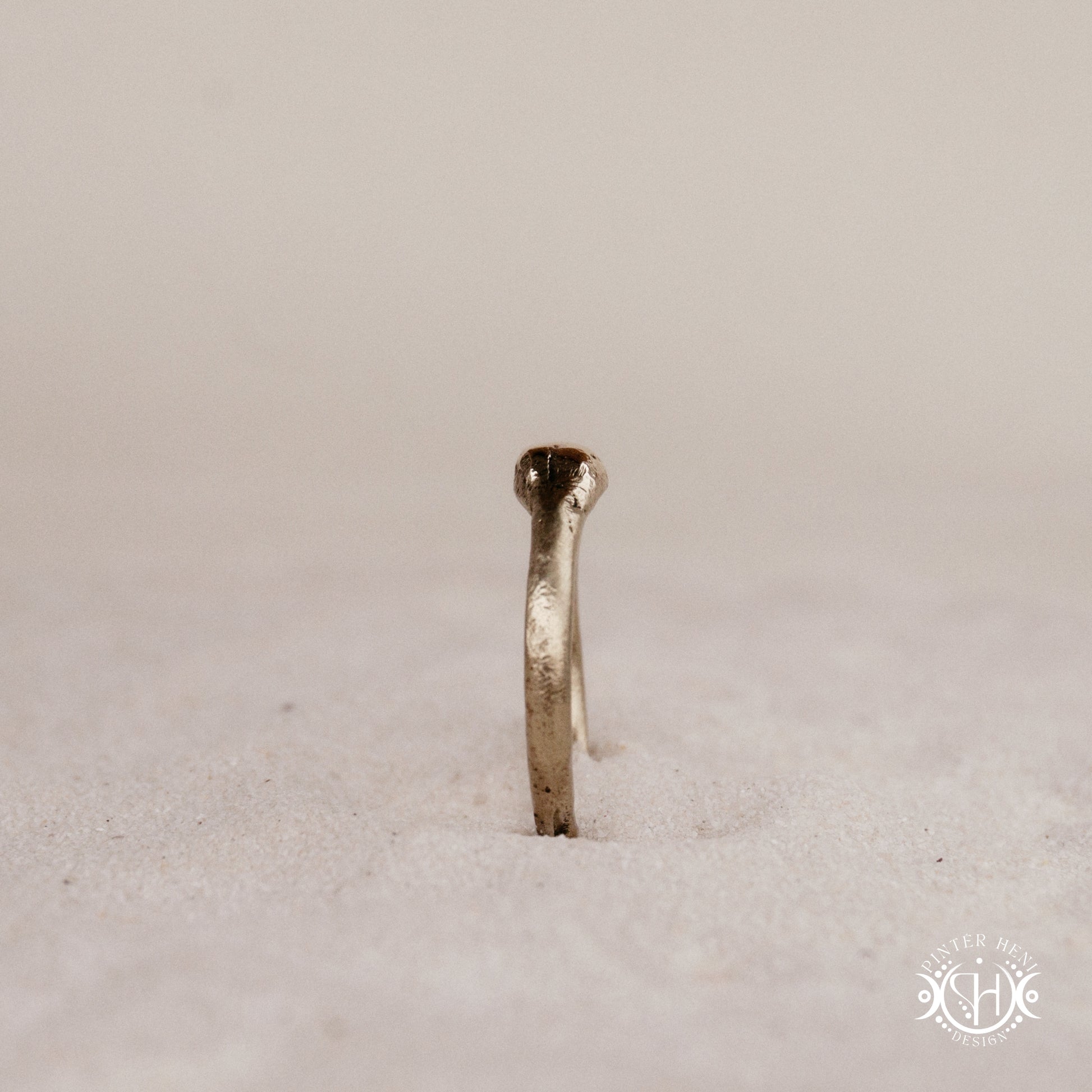 Cairn Ring handmade sandcast brass ring with clustered textured top, rustic ancient-inspired sculptural form, in sand.