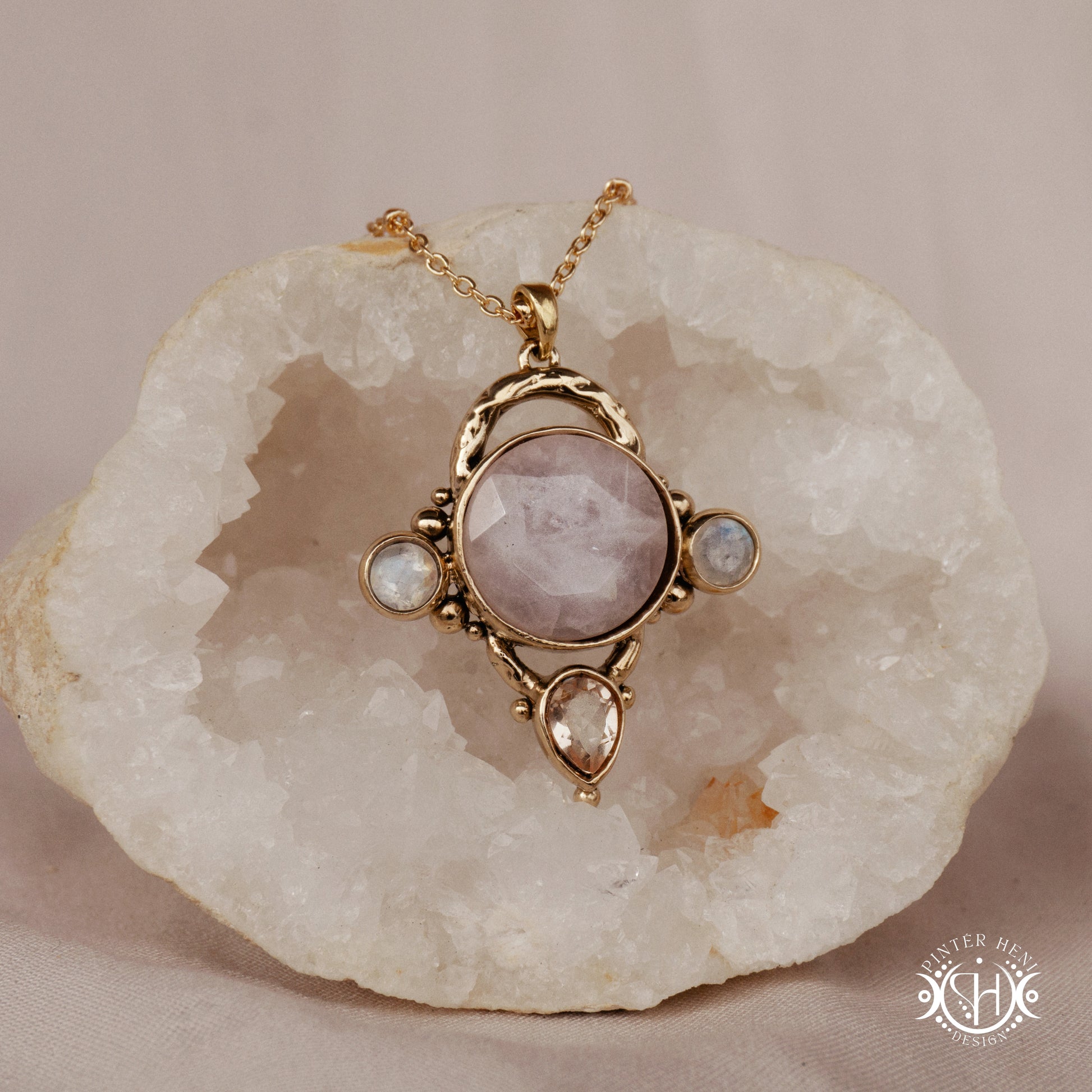 Handmade brass pendant with moonstone, morganite and rose quartz, on a textured stone
