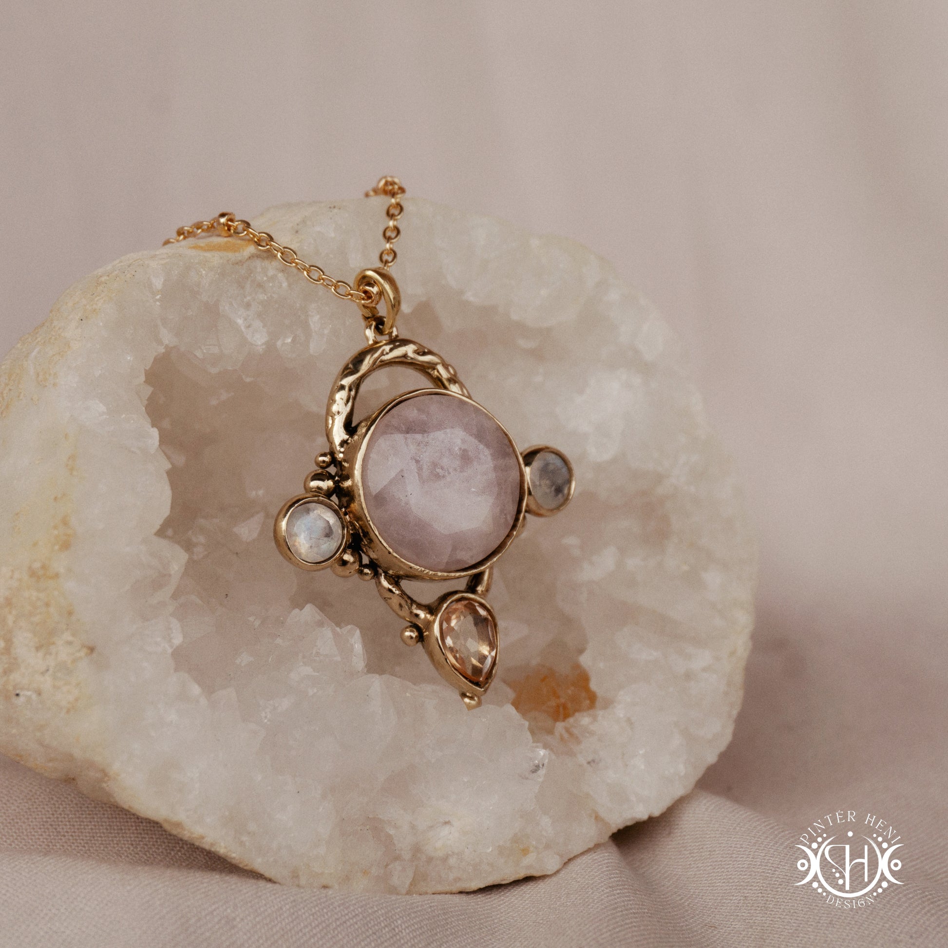 Handmade brass pendant with moonstone, morganite and rose quartz, on a textured stone
