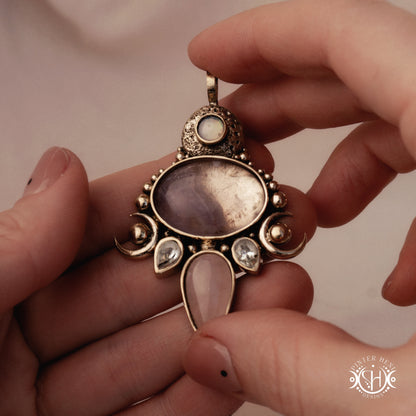 Hand-carved Demeter pendant with rose quartz, amethyst and prasiolite, held in hand.