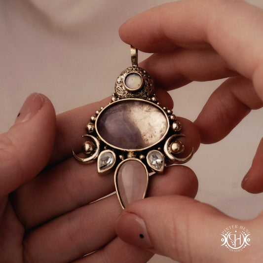 Hand-carved Demeter pendant with rose quartz, amethyst and prasiolite, held in hand.