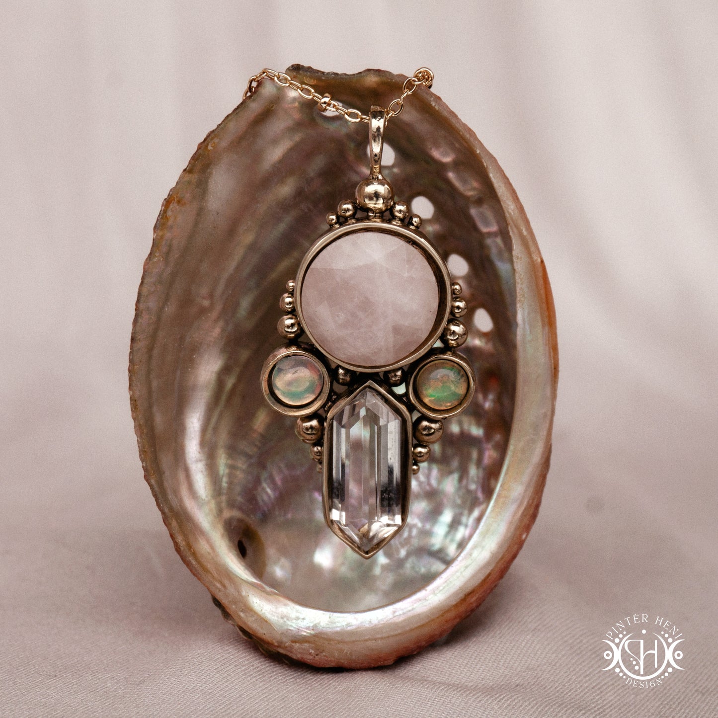 Brass pendant with rose quartz, clear quartz and opal stones, inside a shell.