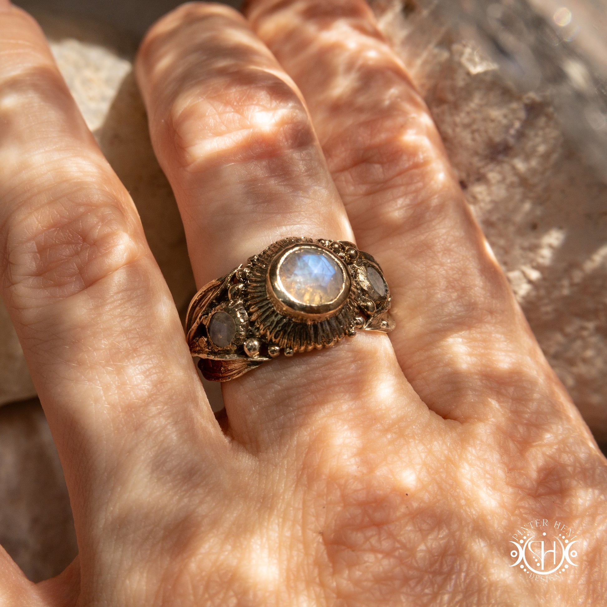 One-of-a-kind brass ring with three rainbow moonstones and sculptural carved band.
