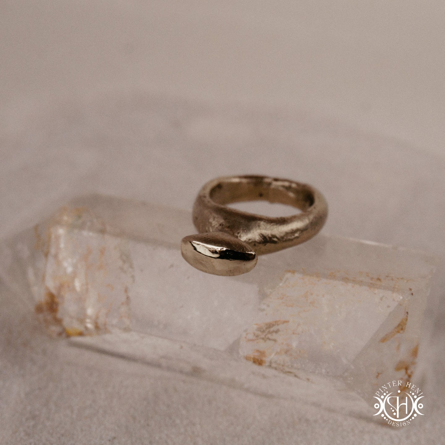Glyph Ring handmade sandcast brass ring with curved sculptural top and ancient symbolic character, on crystal.