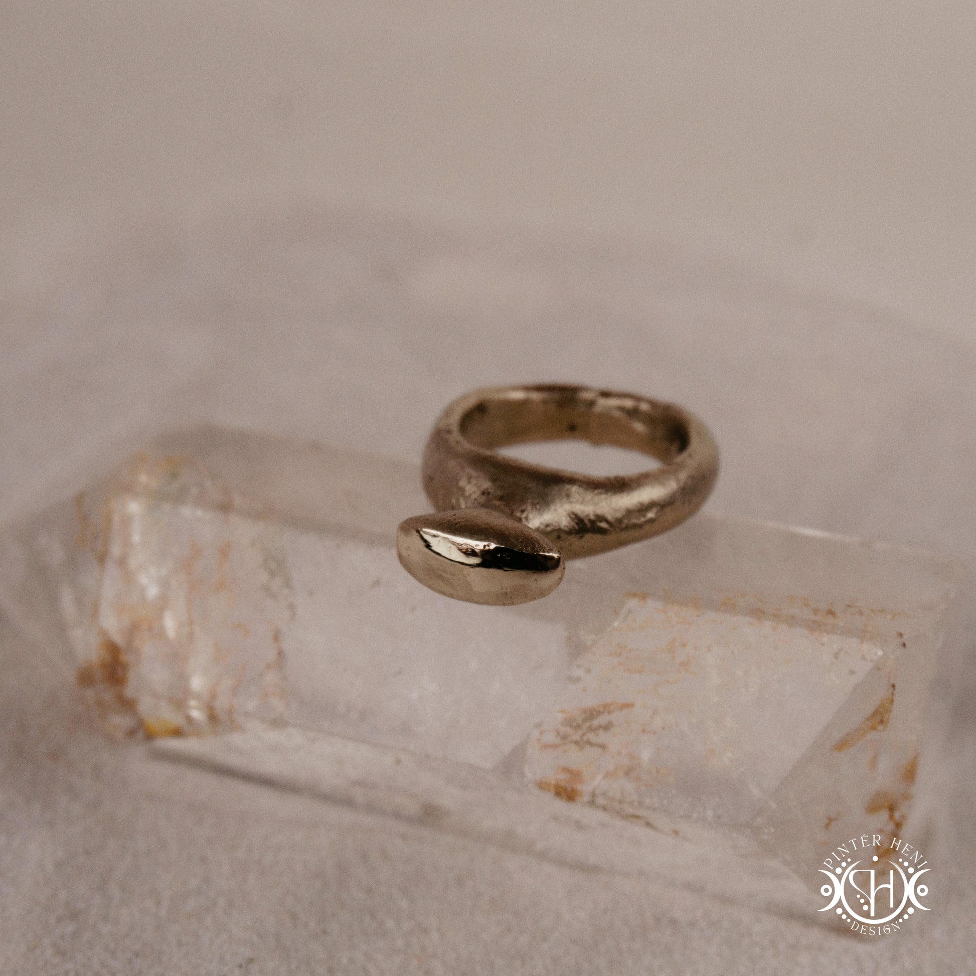 Glyph Ring handmade sandcast brass ring with curved sculptural top and ancient symbolic character, on crystal.