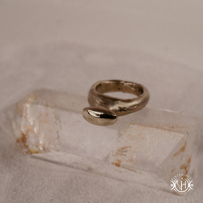 Glyph Ring handmade sandcast brass ring with curved sculptural top and ancient symbolic character, on crystal.