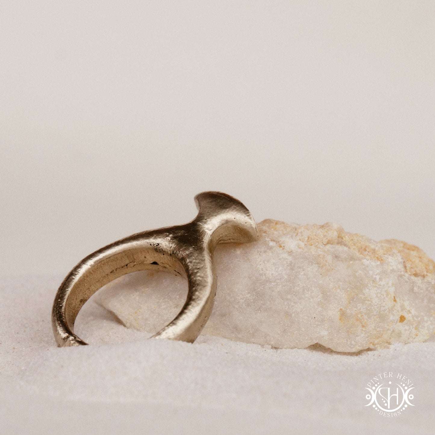 Glyph Ring handmade sandcast brass ring with curved sculptural top and ancient symbolic character, on crystal.