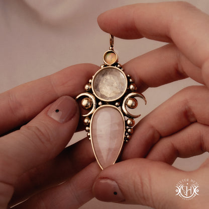 Hand-carved Hecate pendant with rose quartz, rock crystal and opal, held in hand.