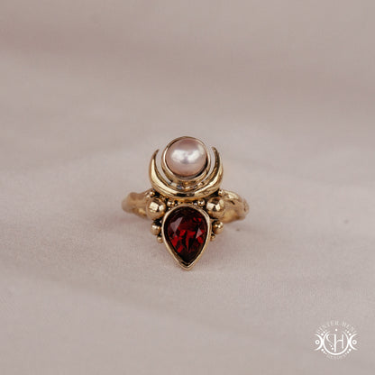 Handmade Hecate ring with garnet and pearl in sculptural feminine design.