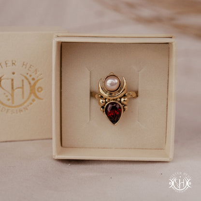 Handmade Hecate ring with garnet and pearl in sculptural feminine design, in branded jewelry box.