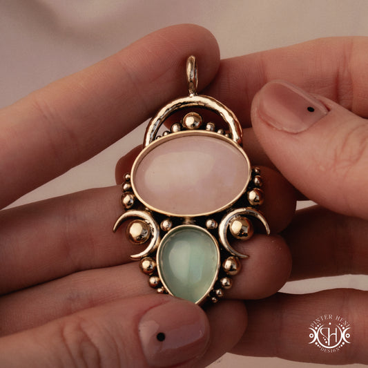 Handmade Hestia pendant with rose quartz and seagreen chalcedony, held in hand.