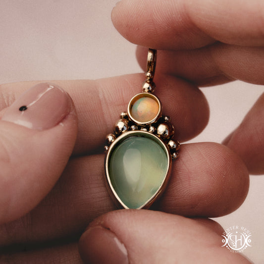 Handmade Kore pendant with sea green chalcedony and opal in brass setting. Made to order in brass, silver or gold, held inhand.