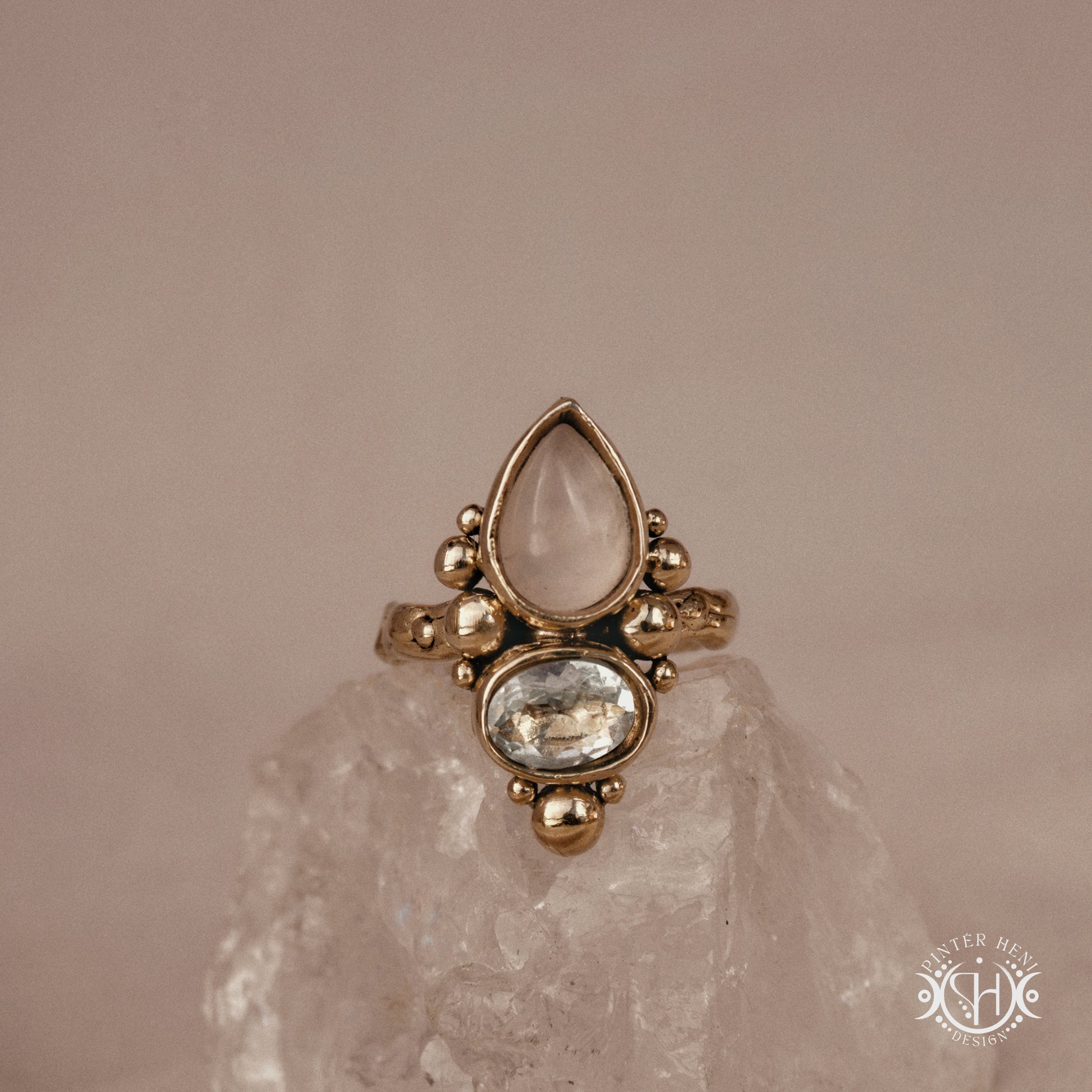 Handmade Kore ring with rose quartz and aquamarine in balanced sculptural setting, on crystal