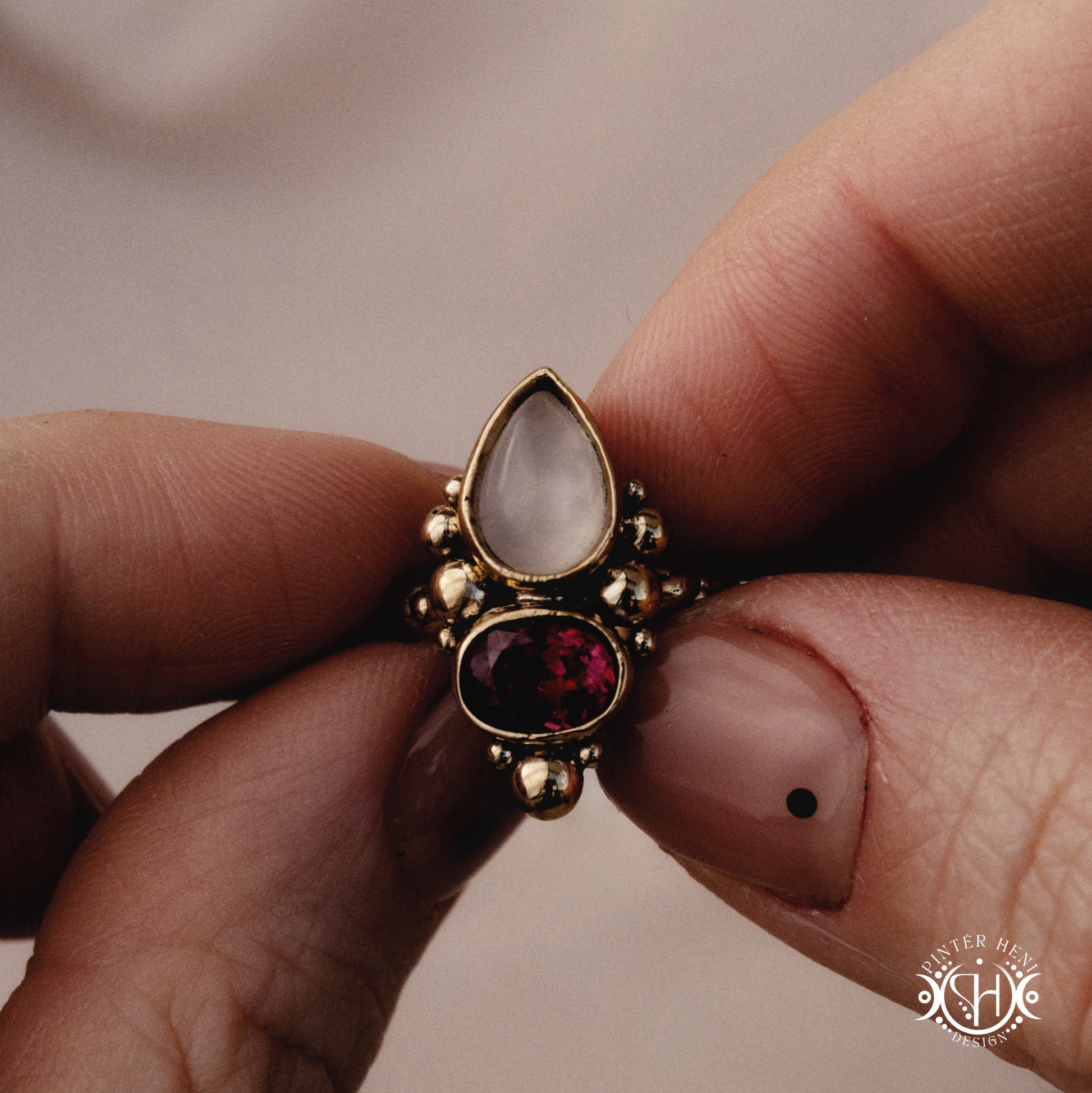 Handmade Korering with rose quartz and garnet in balanced sculptural setting, held in hand.
