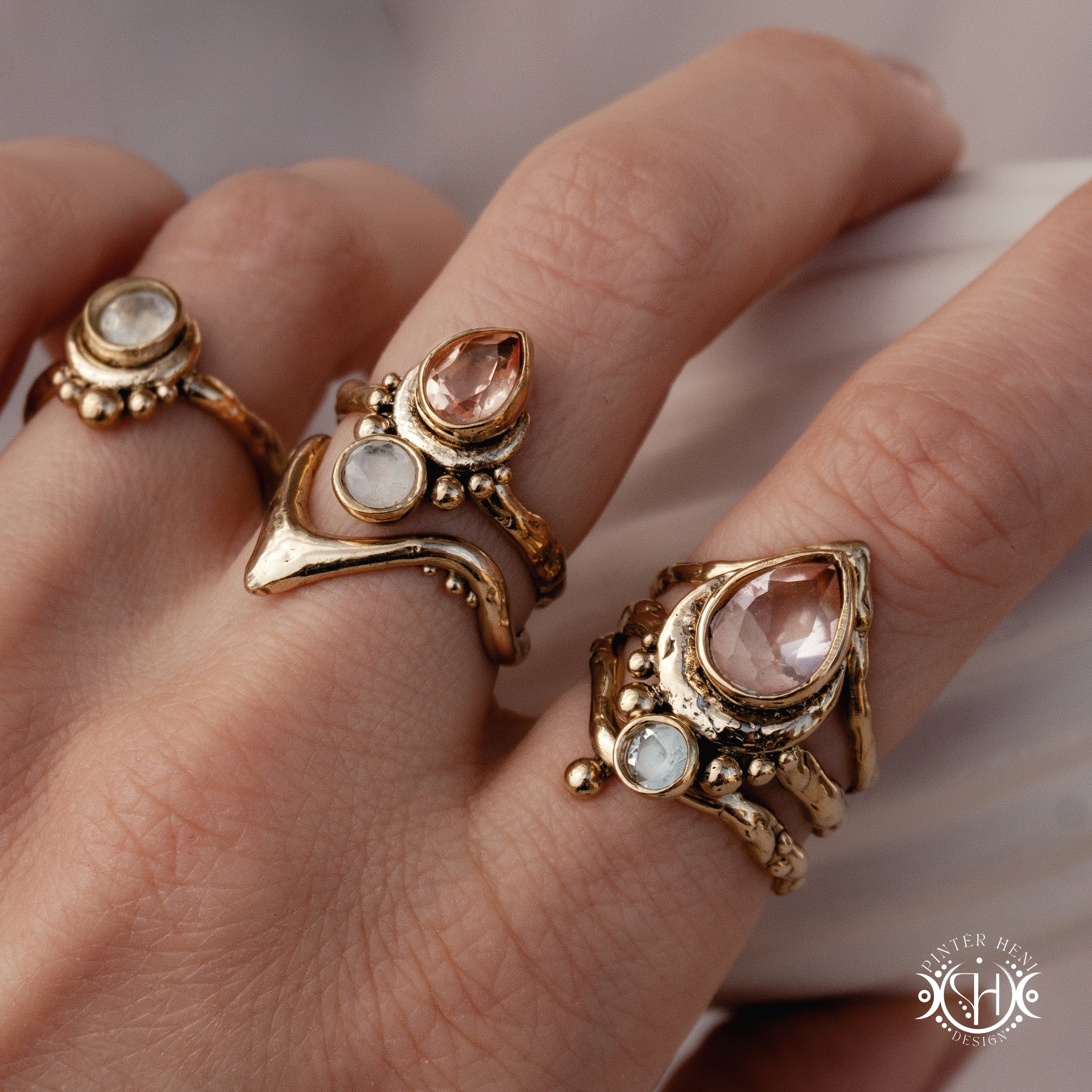 Handmade brass rings with peach colored morganite and moonstone, worn on hand