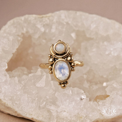 Hand-carved Nyx ring with opal and moonstone in brass, sculptural crescent design, on crystal.