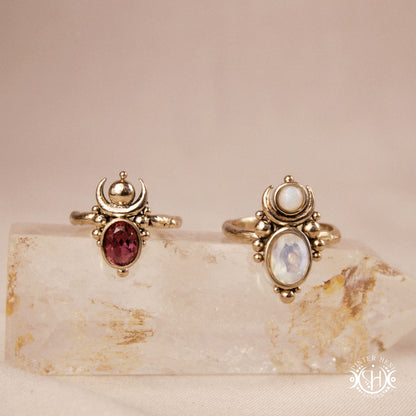 Hand-carved Nyx rings with opal, moonstone and garnet, on crystal.