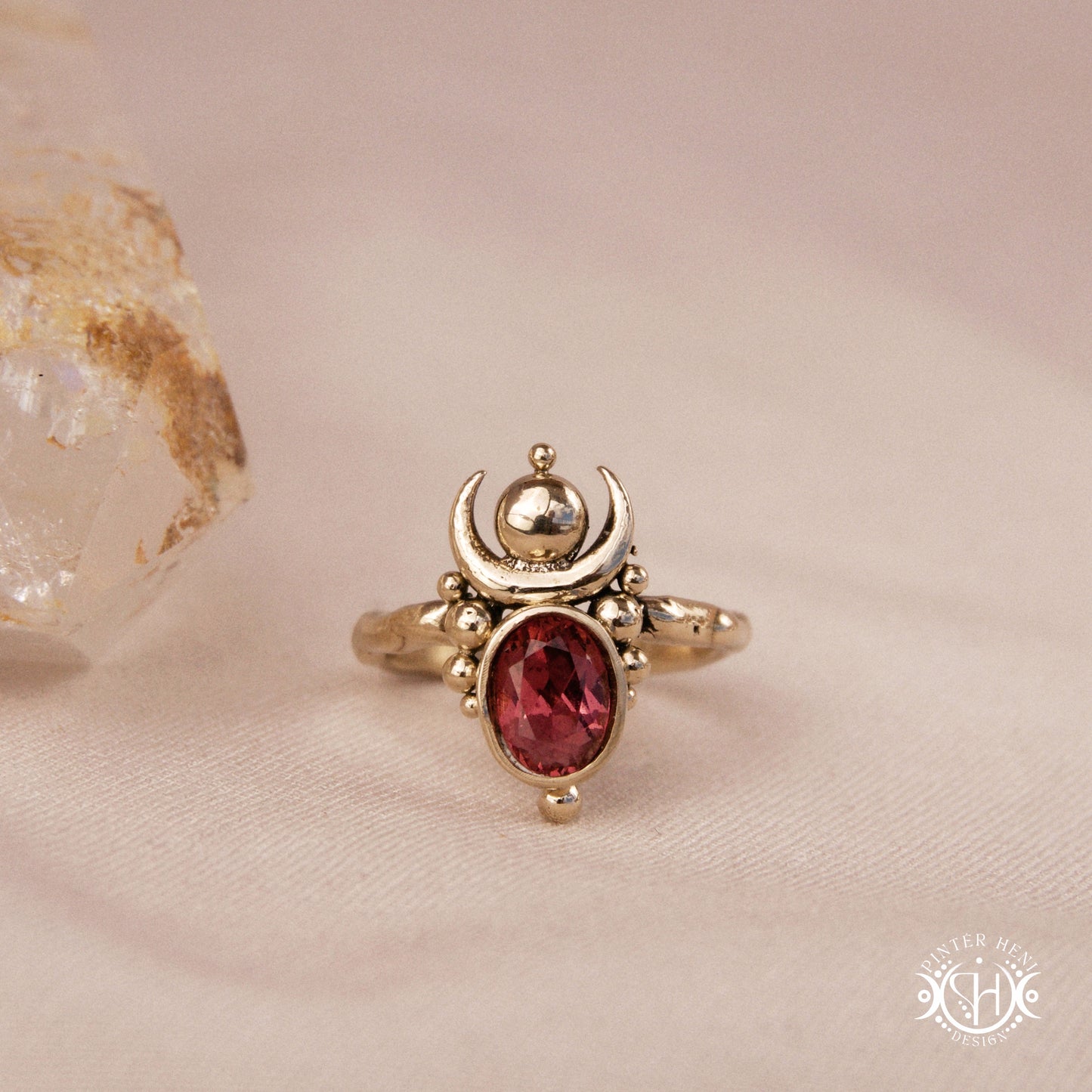 Hand-carved Nyx ring with opal and garnet, compact vertical sculptural form, on beige surface.