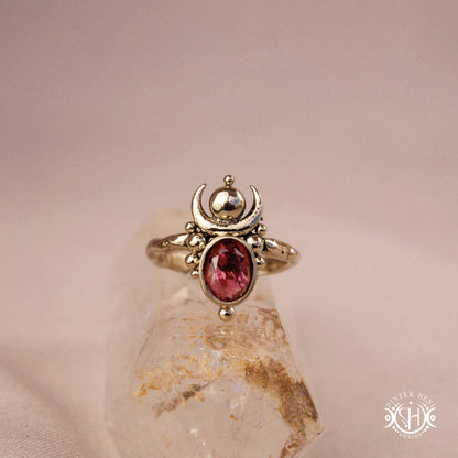 Hand-carved Nyx ring with opal and garnet, compact vertical sculptural form, on crystal.
