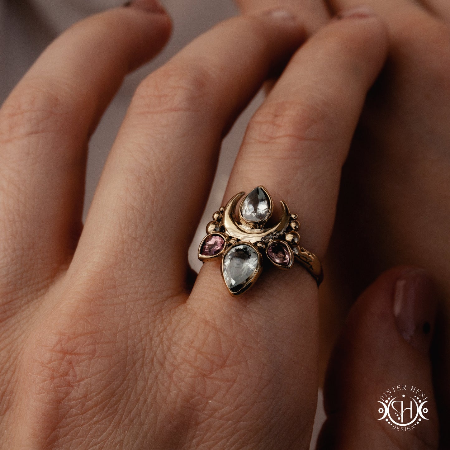 Handmade Persephone ring with aquamarine and pinktourmaline in sculptural feminine setting, worn on hand.