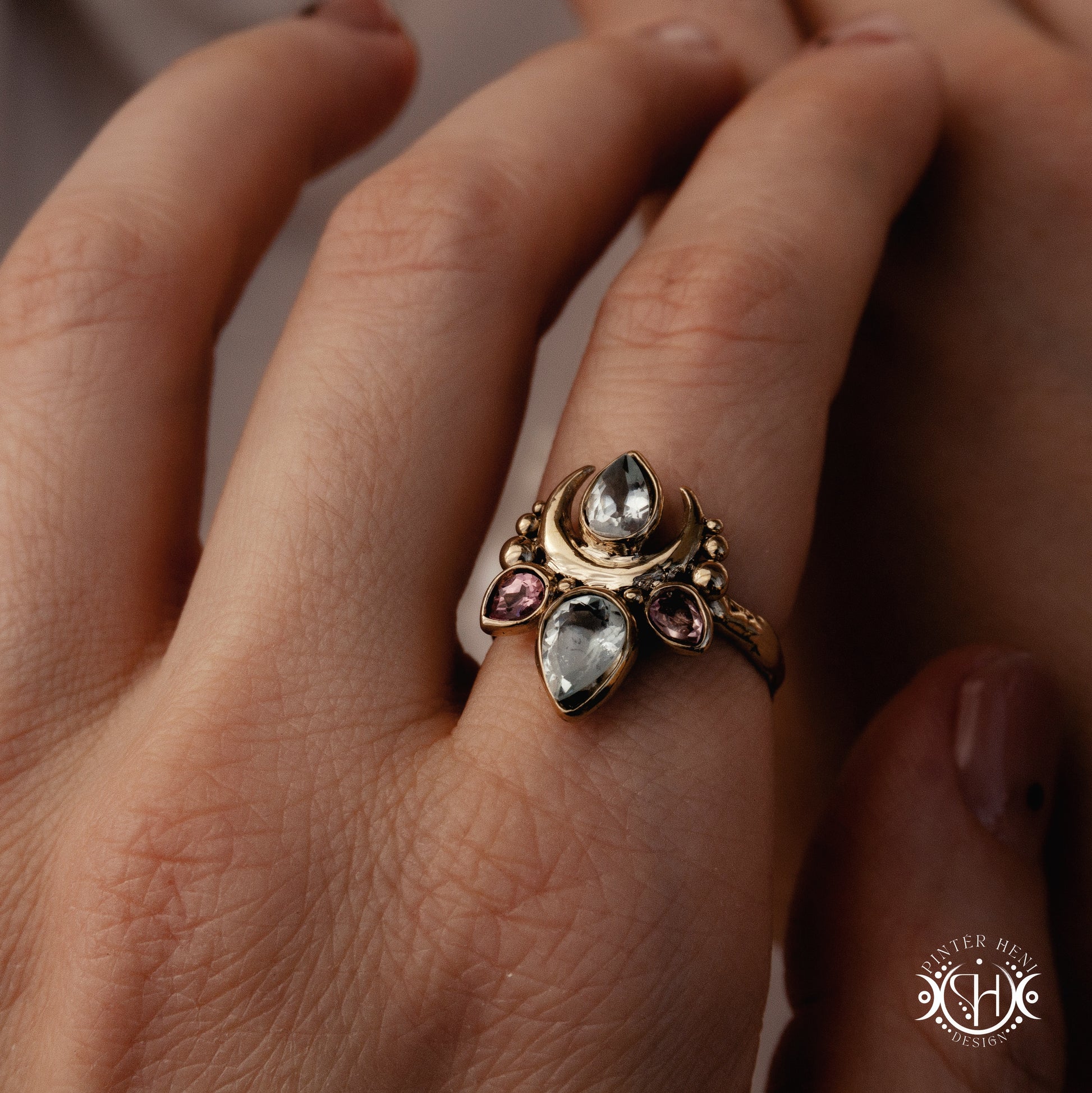 Handmade Persephone ring with aquamarine and pinktourmaline in sculptural feminine setting, worn on hand.