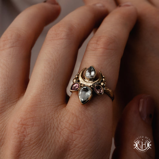 Handmade Persephone ring with aquamarine and pinktourmaline in sculptural feminine setting, worn on hand.