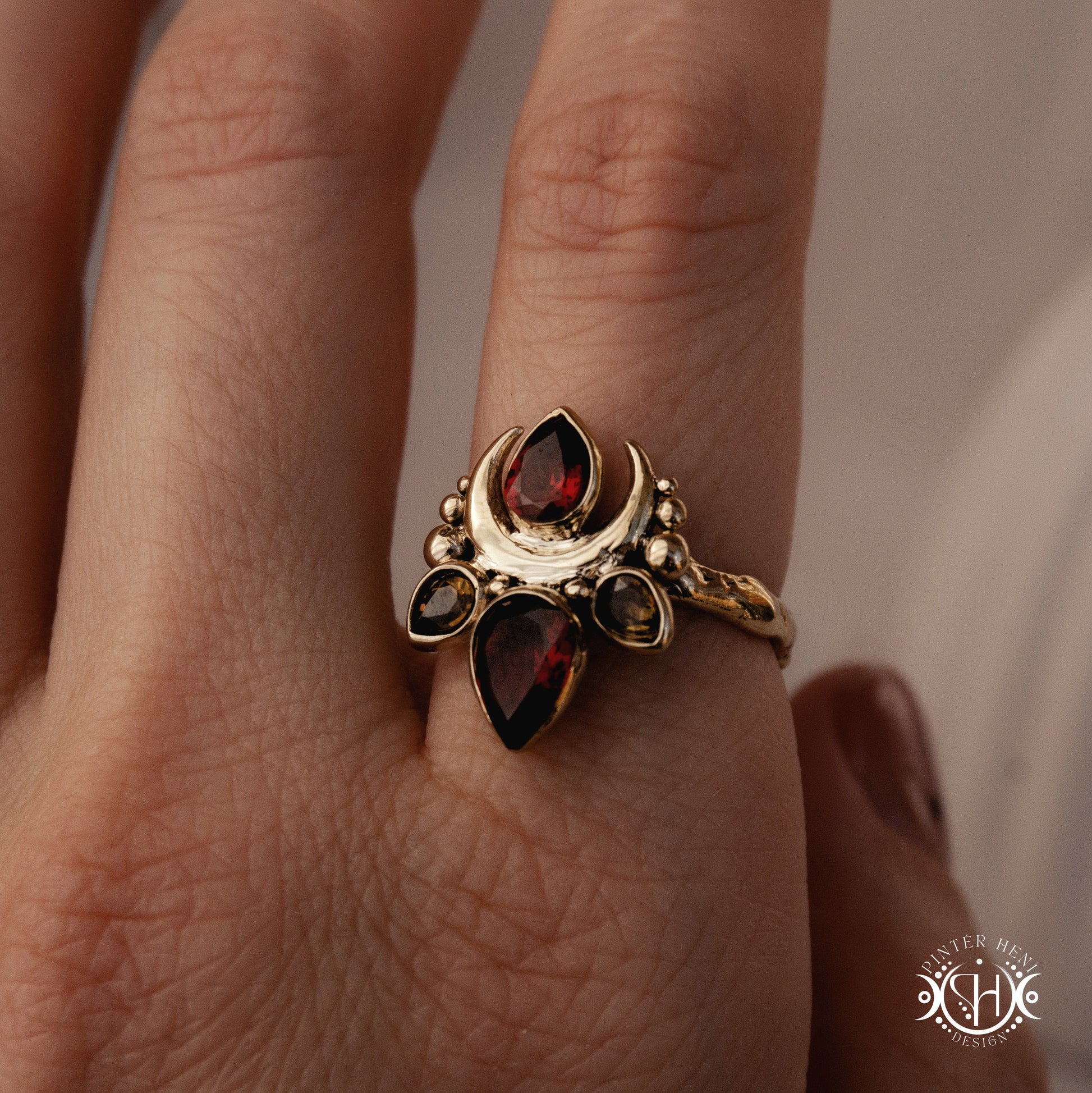 Handmade Persephone ring with garnet and green tourmaline in sculptural feminine setting, worn on hand.