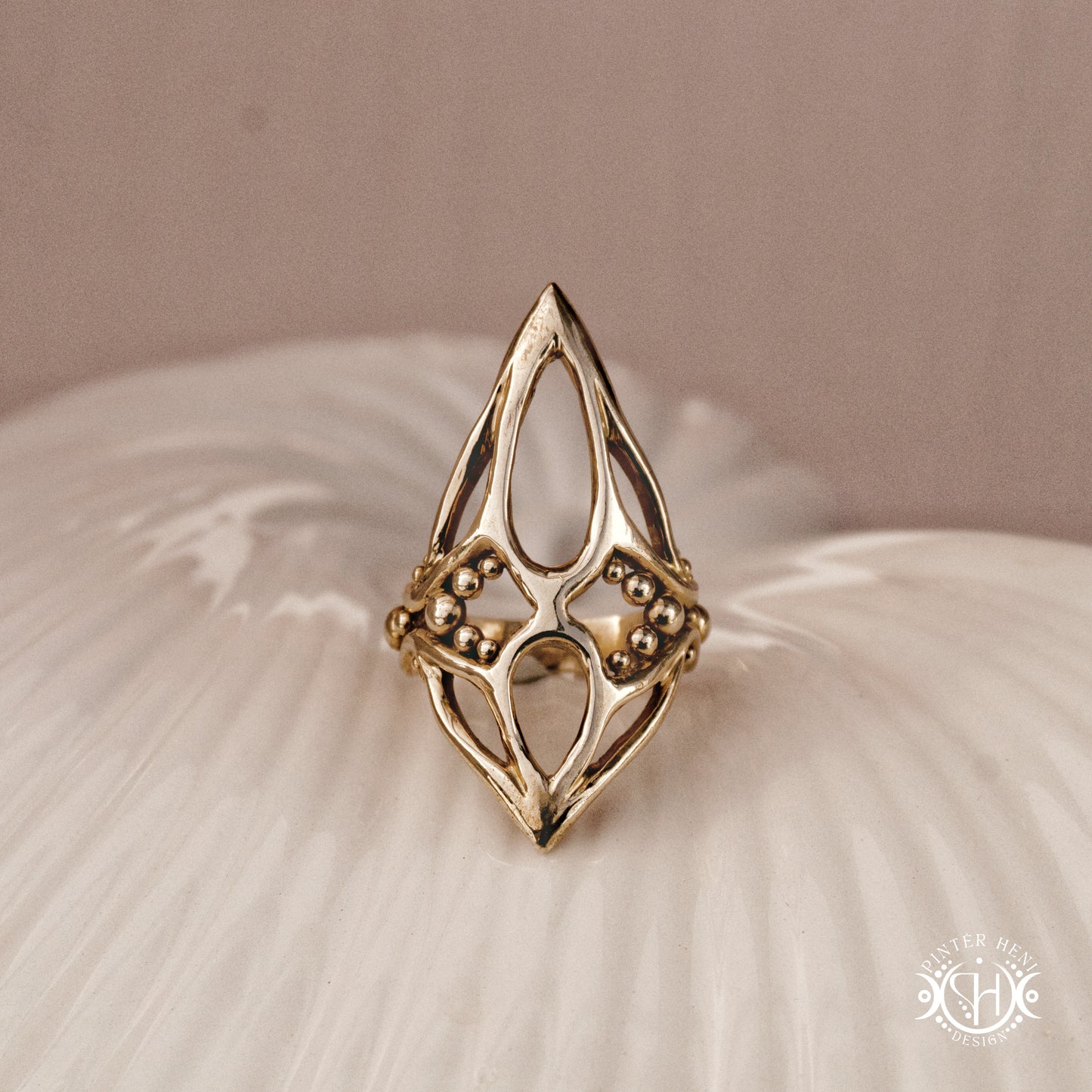 Pulse Ring sculptural axial handmade ring with compact vertical organic form in brass, on ceramic surface.