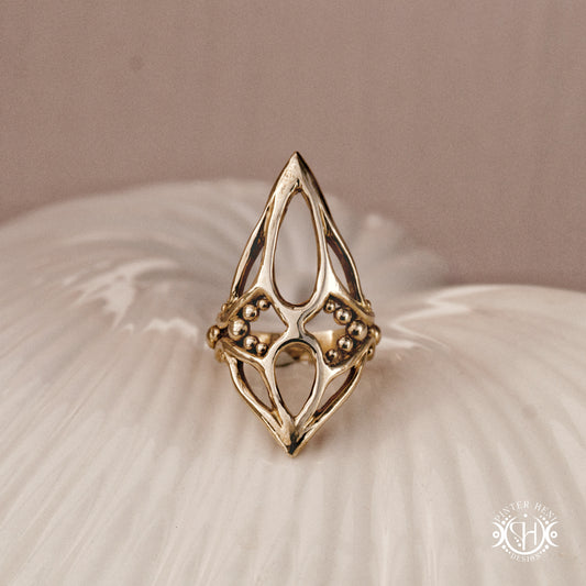 Pulse Ring sculptural axial handmade ring with compact vertical organic form in brass, on ceramic surface.