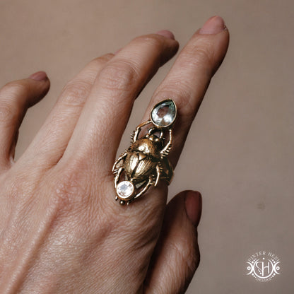 Gold ring with gemstones on a hand against a neutral background