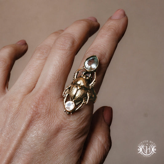 Gold ring with gemstones on a hand against a neutral background