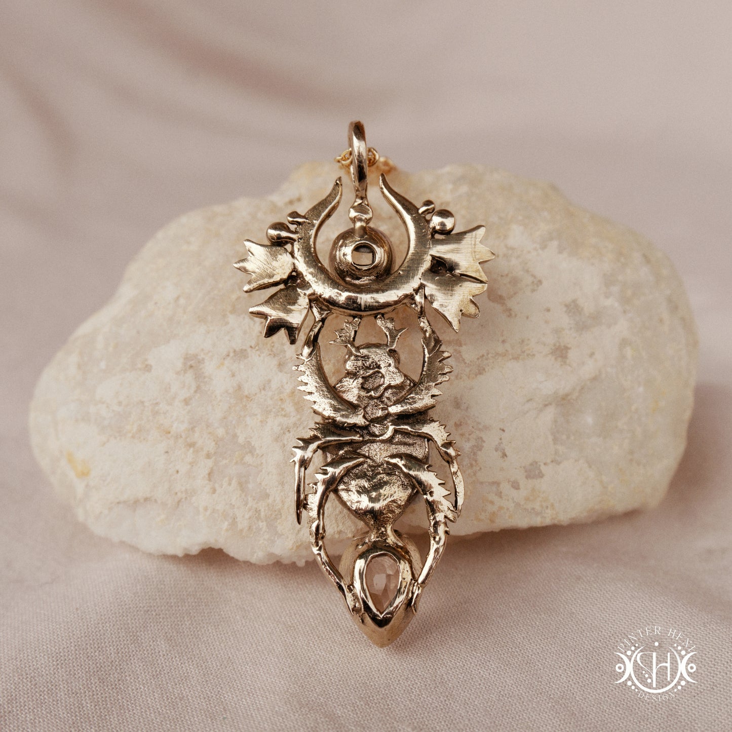 Scarab pendant in brass with moonstone and morganite, back view, on a textured surface