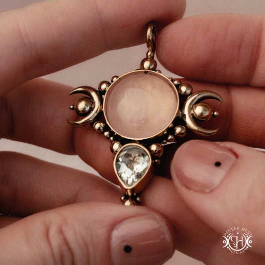 Selene pendant with rose quartz and prasiolite held between fingers against a neutral background