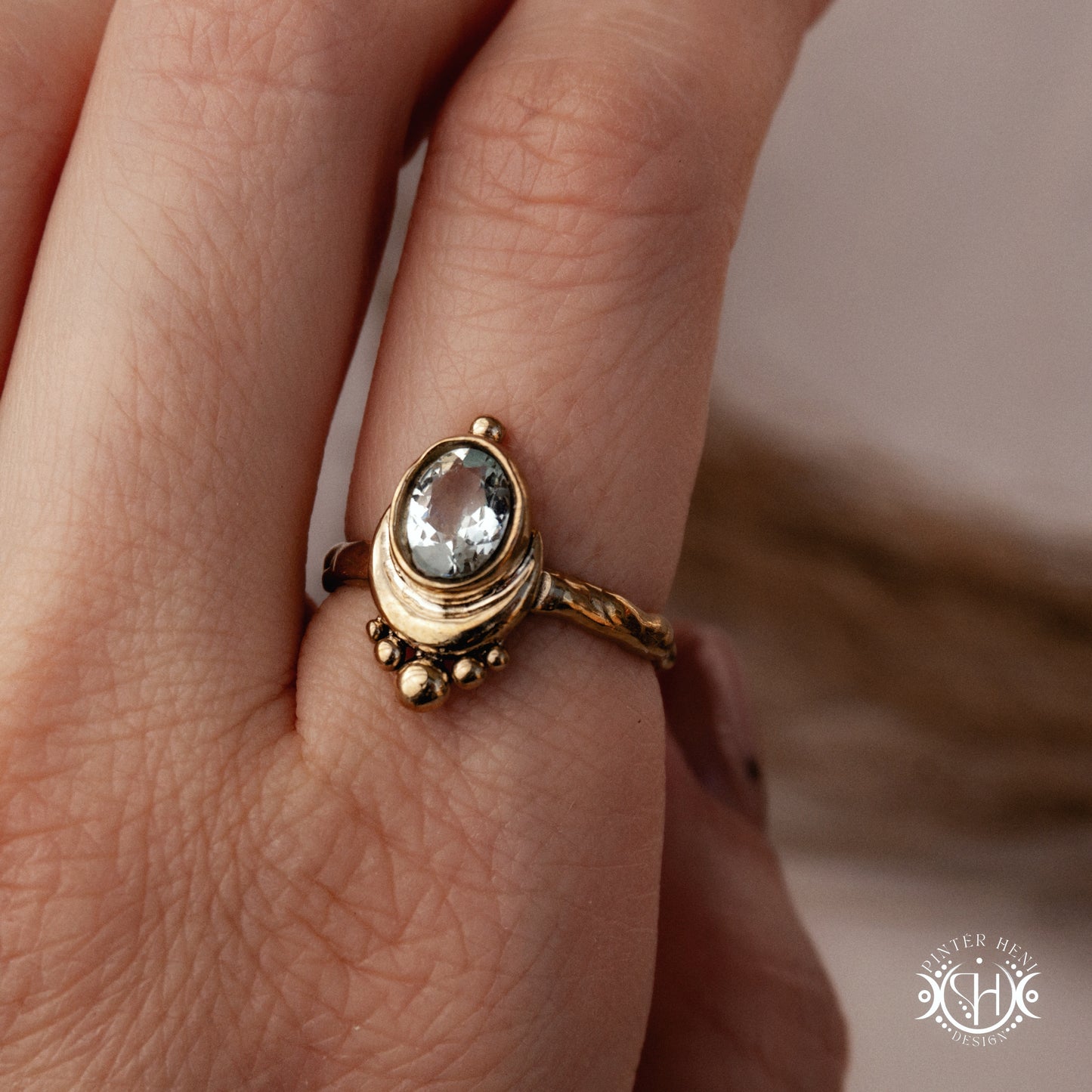 Handmade oval aquamarine gemstone ring set within a crescent-inspired form, worn on hand.