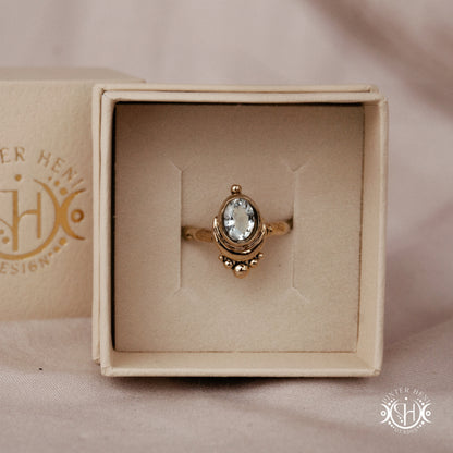 Handmade oval aquamarine gemstone ring set within a crescent-inspired form, in branded jewelry box.