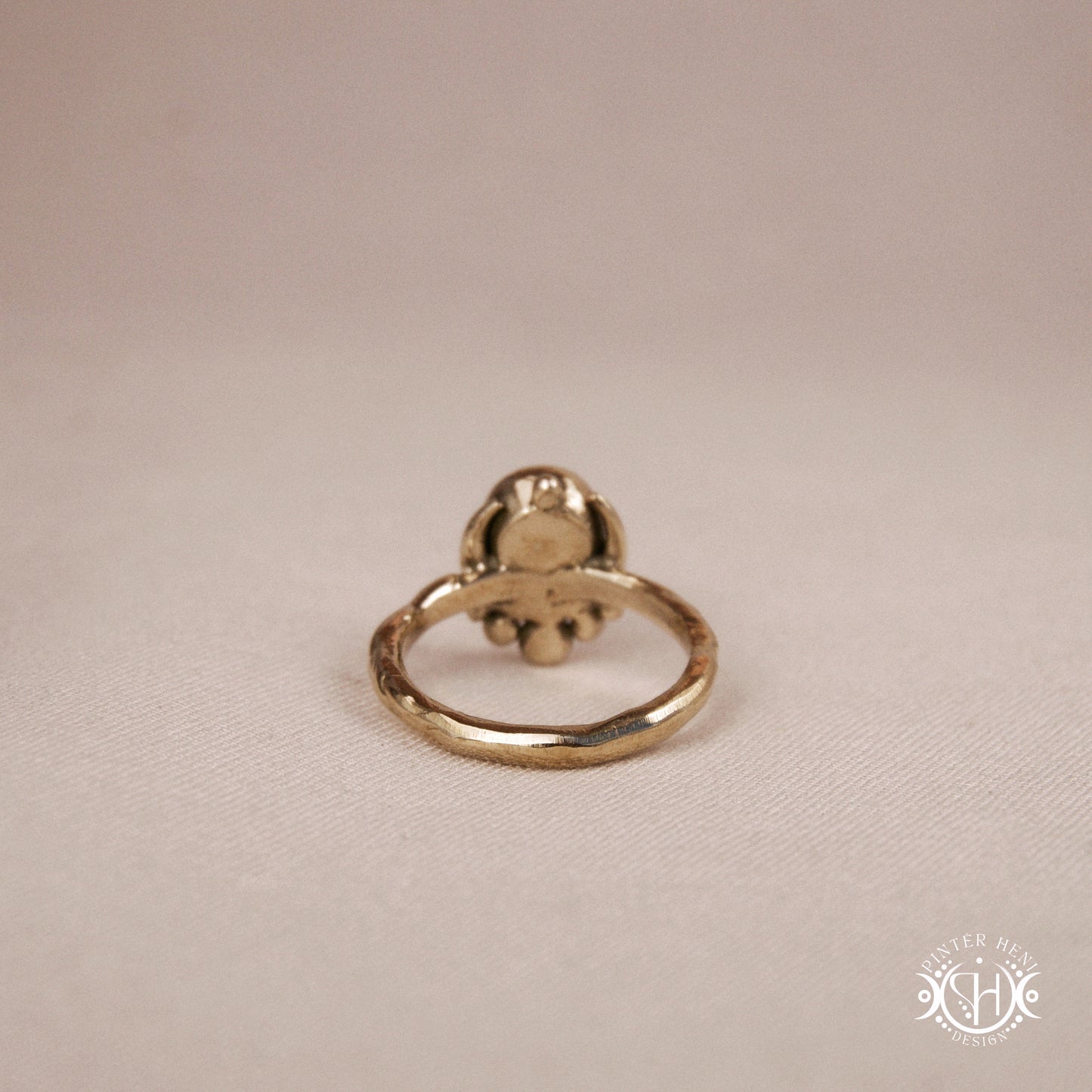 Handmade crescent moon ring with round moonstone set inside the lunar curve, on beige textile.