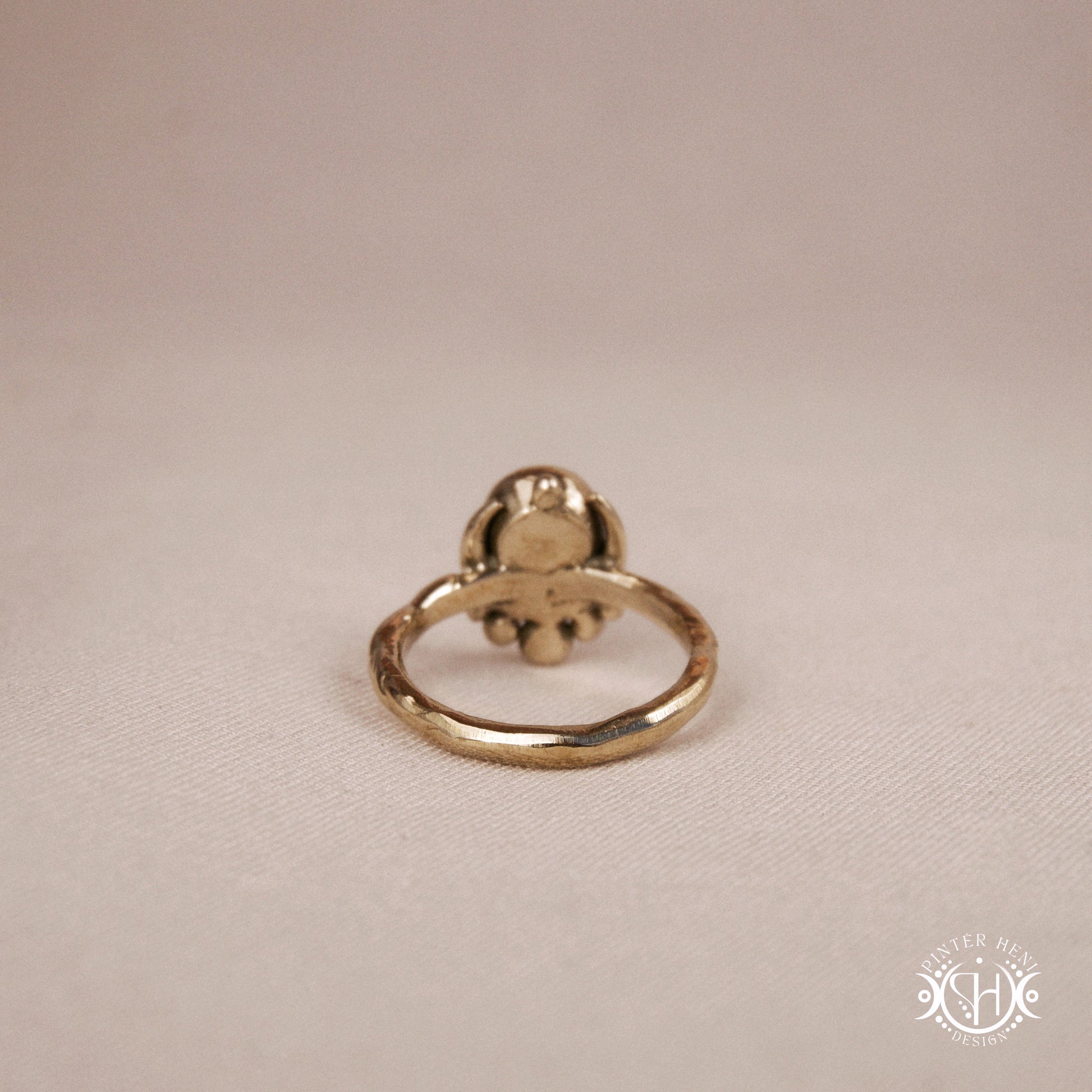 Handmade crescent moon ring with round moonstone set inside the lunar curve, on beige textile.