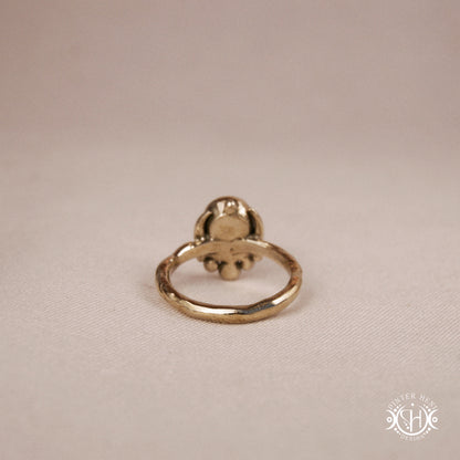 Handmade crescent moon ring with round moonstone set inside the lunar curve, on beige textile.