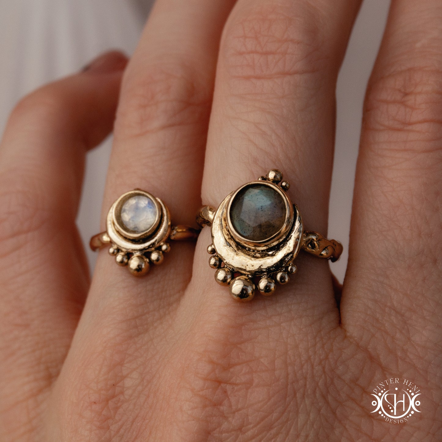 Handmade crescent moon ring with round moonstone set inside the lunar curve, worn on hand.