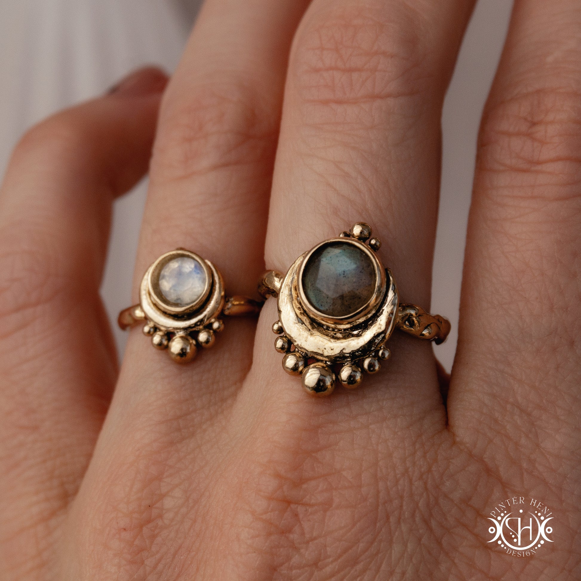 Handmade crescent moon ring with round moonstone set inside the lunar curve, worn on hand.
